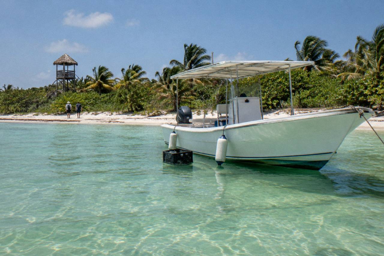 Isla Contoy: a tour boat anchored in clear shallow water off the national park beach